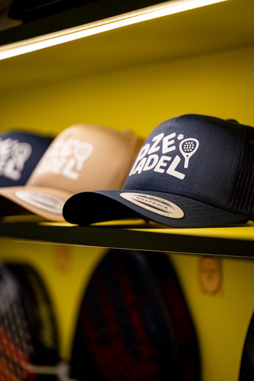 Casquettes floquées ZE PADEL exposées au Pro Shop du club