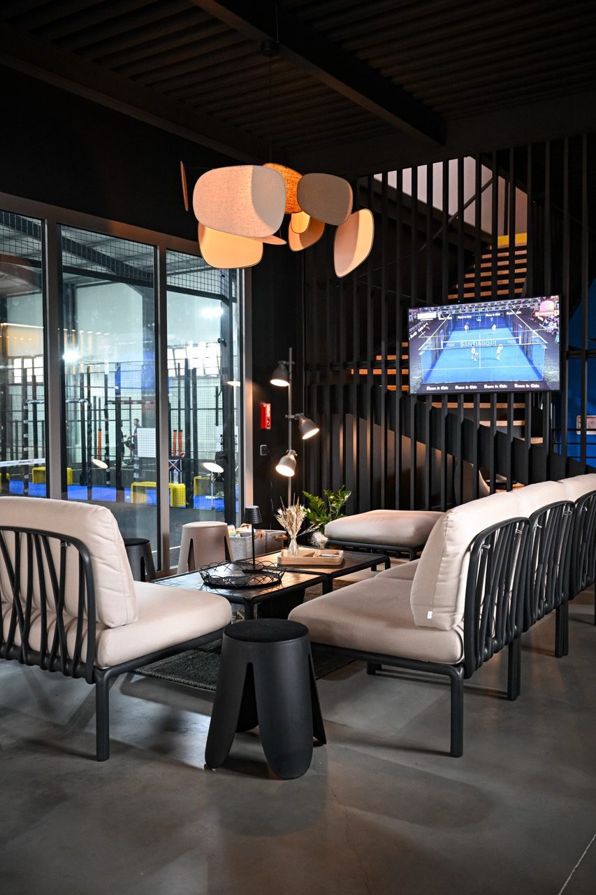 Espace lounge avec fauteuils et vue sur les pistes du club house ZE PADEL