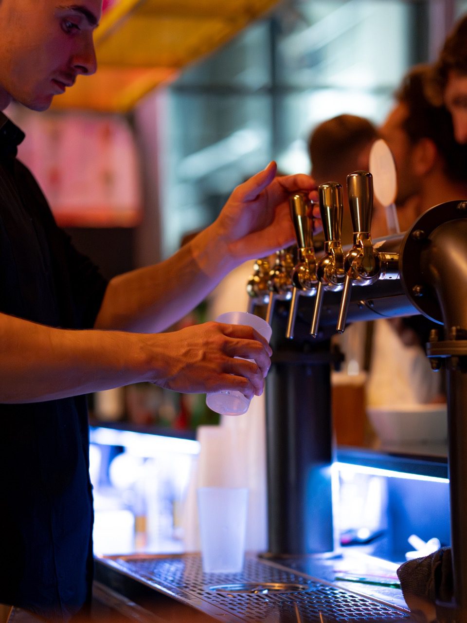Barman servant une bière pression au bar du ZE PADEL Social Club